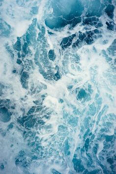 image ID: a close up of crashing water. it is a swirl of white and blues as waves crash against each other in blues and whites