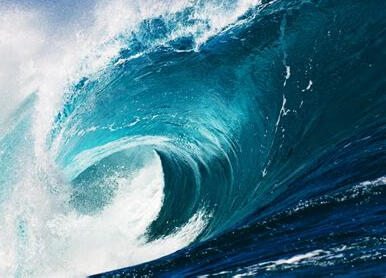 image ID: an incoming wave from a side view. there's white foam at the top left and the wave is a teal to dark blue gradient